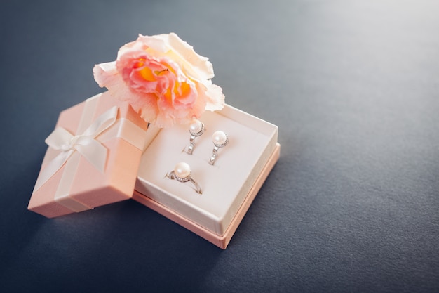 Satz Perlenschmuck in Geschenkbox mit Blumen. Silberohrringe und Ring mit Perlen als Geschenk für den Urlaub.