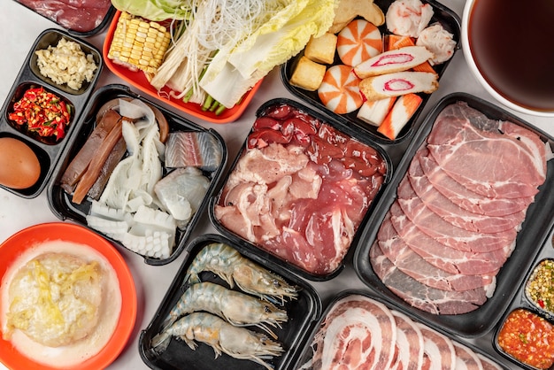 Satz rohes Schweinefleisch und Meeresfrüchte auf Teller und Gemüse, Suppe für Sukiyaki