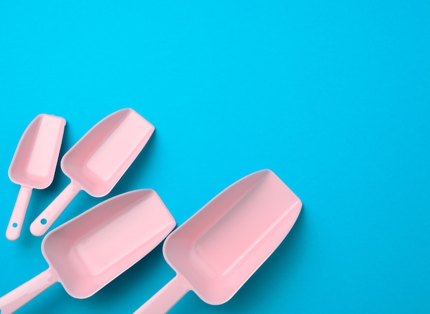 Satz rosa Plastikküchenschaufeln für Massenprodukte auf einem blauen Hintergrund, flache Lage