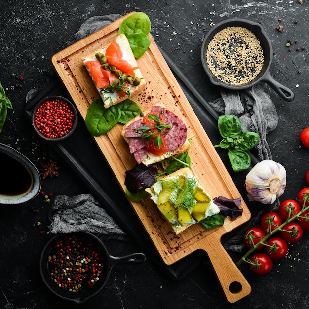 Satz Sandwiches mit Gemüse und Lachs auf einem Holzbrett Draufsicht Rustikaler Stil