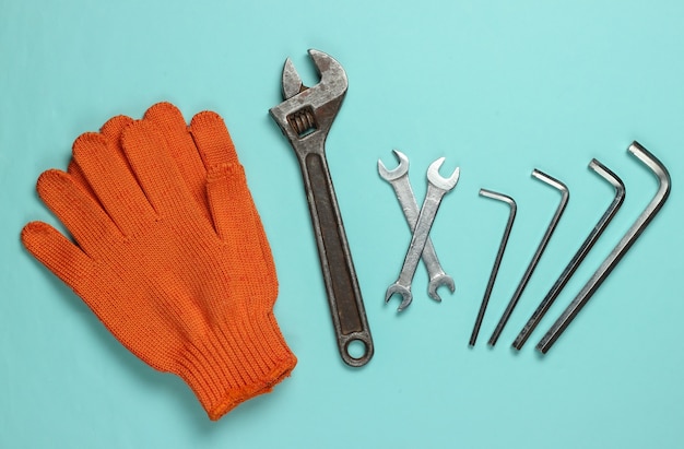 Satz Schraubenschlüssel und Handschuhe auf blauem Hintergrund. Arbeitswerkzeug. Draufsicht