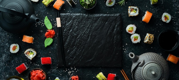 Satz Sushi-Rollen mit Ingwer-Wasabi und Sojasauce auf schwarzem Steinhintergrund Japanische traditionelle Küche Draufsicht Rustikaler Stil