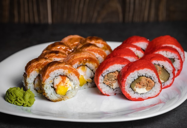 Satz Sushi-Rollen mit Wasabi-Käse und Ingwer und Lachs auf einem weißen Teller