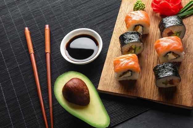 Satz Sushi- und Maki-Rollen mit geschnittener Avocado auf Steintisch. Ansicht von oben.