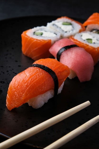 Satz traditionelles japanisches Nahrungsmittelsushi mit rotem Fisch am schwarzen Tisch