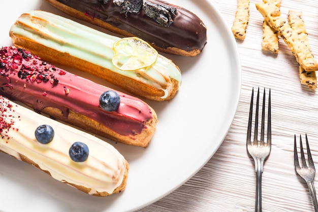 Satz verschiedene Eclair-Kuchen auf Holztisch