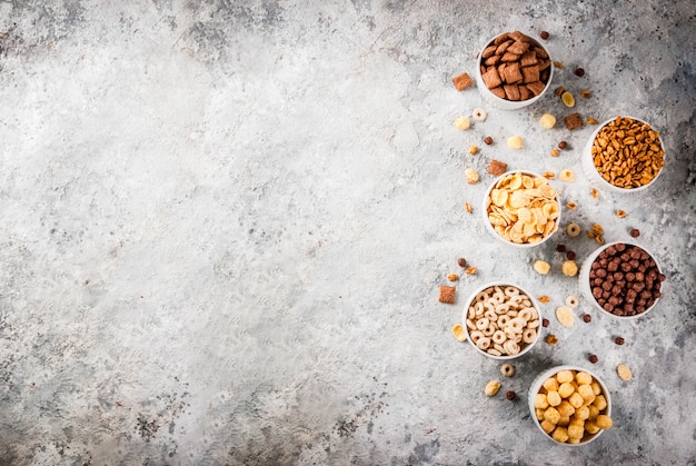 Satz verschiedene Frühstückskost aus Getreide Corn Flakes, Hauche, Knalle, Draufsicht des grauen Steintabellen-Kopienraumes