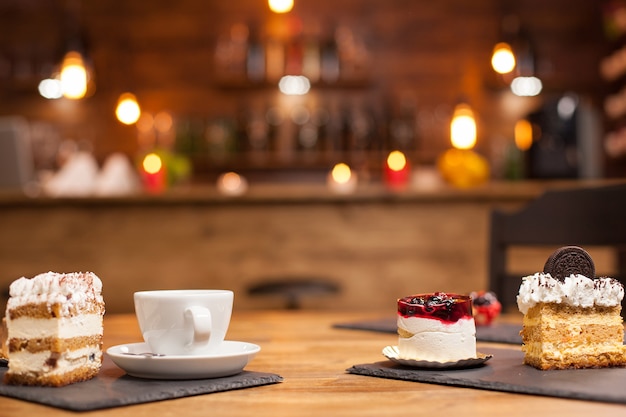 Satz verschiedene Kuchen und Desserts frisch gebacken auf Holztisch arrangiert. Leckerer Kuchen mit natürlichen Früchten obendrauf. Tasse leckeren Kaffee. Kuchenstück mit Biskuit darüber.