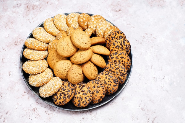 Satz verschiedene Plätzchen der amerikanischen Art auf einem Leichtbetonhintergrund. Shortbread mit Konfetti, Sesam, Erdnussbutter, Haferflocken und Schokoladenkeksen.