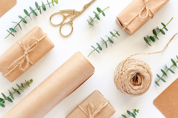 Satz von Materialien zum Verpacken von Weihnachtsgeschenken. Kraftpapier, Juteschnur, Schere, Kisten und Zweige aus grünem Eukalyptus