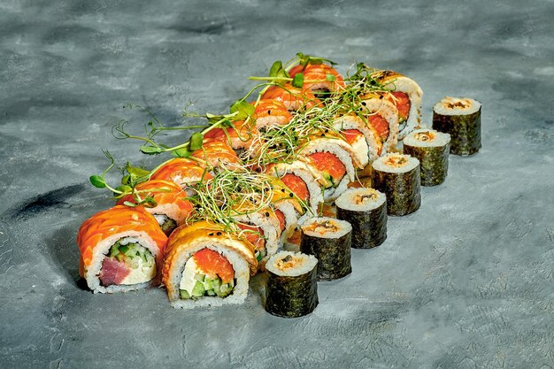 Satz von Sushi-Rollen mit verschiedenen Füllungen auf grauem Hintergrund