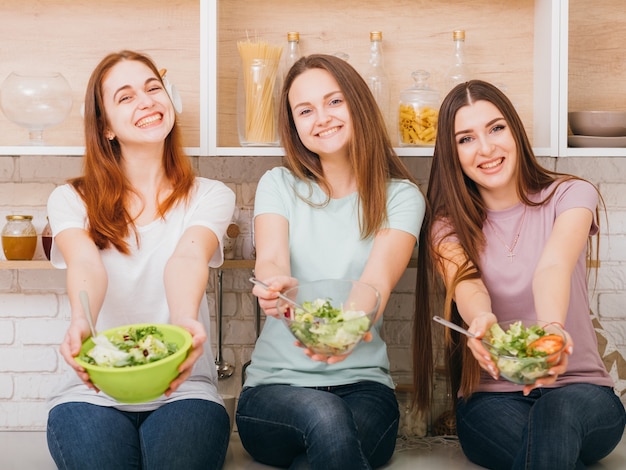 Sauber essen. Bio-Rezept. Gesunde Vollwerternährung. Lächelnde junge Frauen mit Salatschüsseln in den Händen.