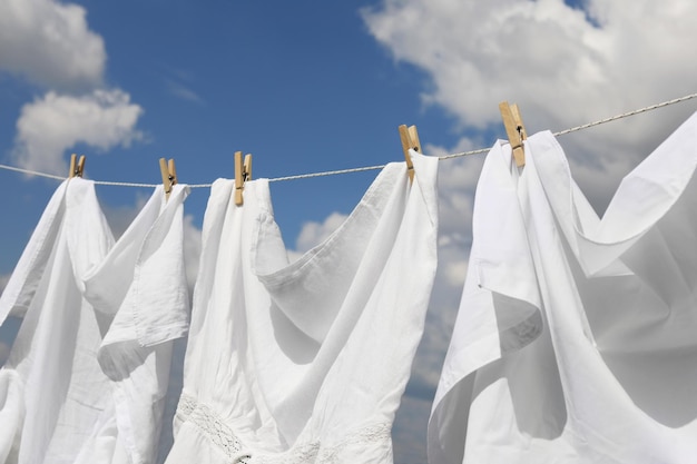 Saubere Kleidung, die an der Wäscheleine gegen den Himmel hängt Trocknen von Wäsche