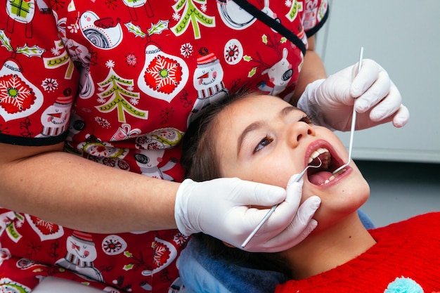 Saubere Klinik des kleinen Mädchens der Behandlungsbürokinderzahnarztzähne jugendlich roten Doktors des neuen Jahres der Rabattfrau ruhig bequem