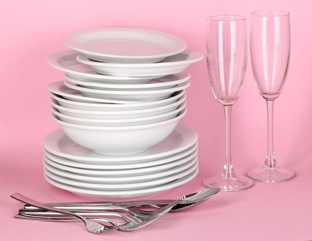 Saubere weiße Geschirr auf rosa Hintergrund