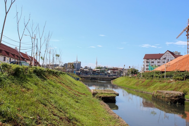 Sauberer städtischer Fluss mit grünem Gras an den Ufern