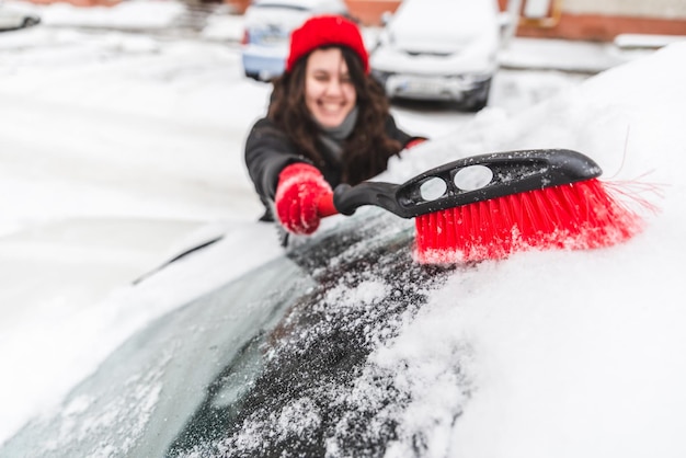 Sauberes Auto der Frau mit Bürste nach Schnee