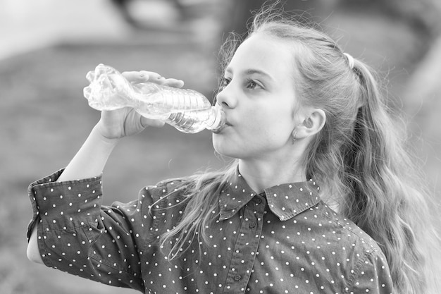 Sauberes Wasser ist eine lebenswichtige Ressource für die menschliche Existenz. Kleines Mädchen trinkt einen Tropfen Wasser. Durstiges Kind trinkt frisches Wasser aus einer Plastikflasche. Löscht seinen Durst mit natürlichem Mineral- oder Trinkwasser