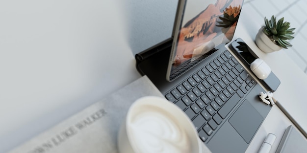 Sauberes weißes Büro mit einem Laptop auf dem Tisch und Arbeitsgeräten 3D-Rendering-Illustration