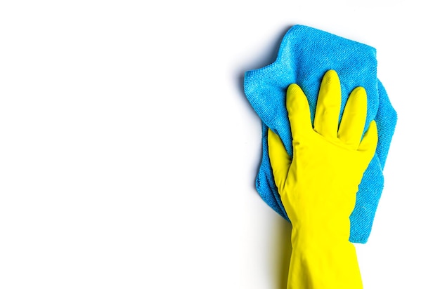 Sauberkeit und Reinigung. weibliche hand in gelben handschuhen und blauem reinigungstuch auf weißem hintergrund mit kopienraum draufsicht