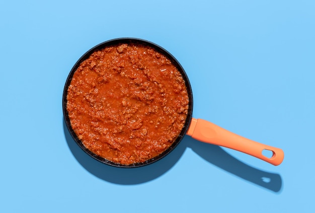 Sauce Bolognese Draufsicht Pfanne mit Ragu-Sauce auf blauem Hintergrund