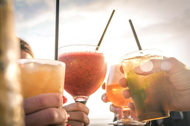 Foto saudações aos melhores amigos um grupo de amigos desfrutando de bebidas à noite na praia ao pôr do sol