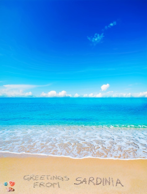 Saudações da sardenha escritas em uma praia tropical