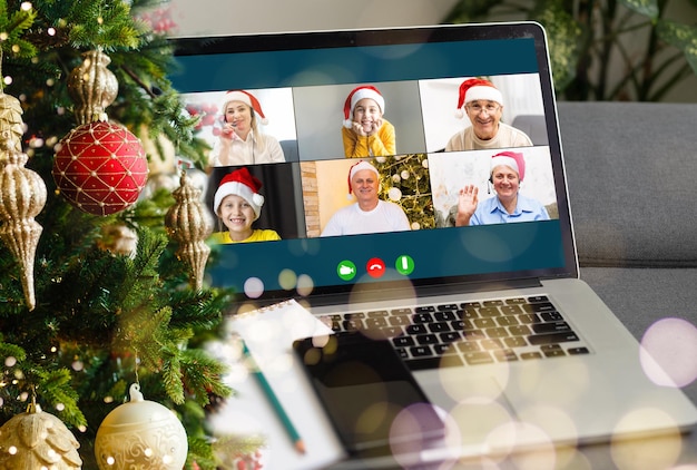 Saudações de Natal on-line. uma mulher com um suéter branco e chapéu de Papai Noel vermelho usa um laptop para fazer chamadas de vídeo para amigos, pais e fazer compras online.
