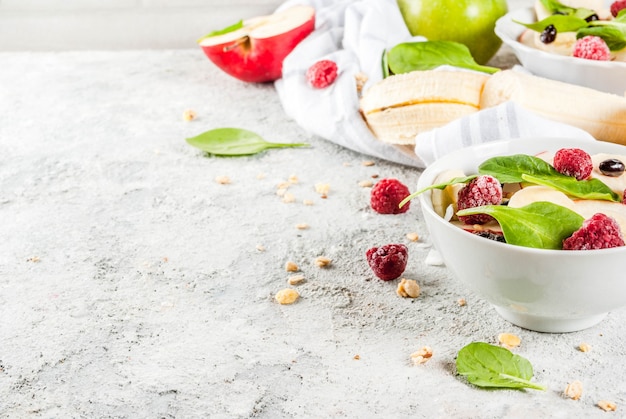 Foto saudável café da manhã de verão, salada de frutas e bagas com espinafre, granola, maçã e banana