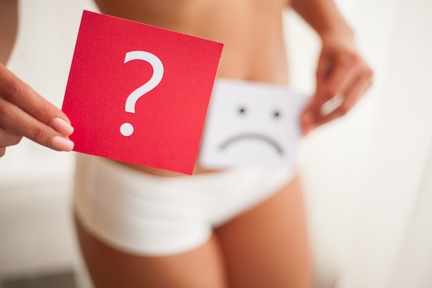 Saúde. corpo de mulher em roupa interior com cartão de pergunta perto da barriga