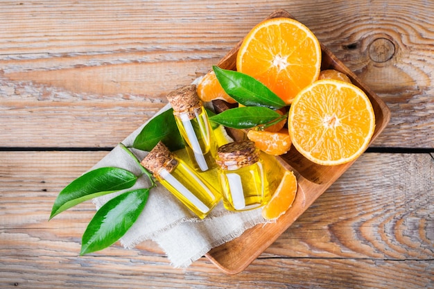 Saúde e beleza ainda conceito de vida Óleo essencial orgânico de tangerina tangerina clementina em um pequeno frasco de vidro com folhas verdes e frutas laranja em uma mesa de madeira rústica Vista superior plana sobre a cabeça