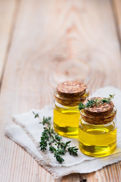 Saúde e beleza ainda conceito de vida Óleo essencial orgânico de tomilho em um pequeno frasco de vidro com folhas verdes em um fundo de espaço de cópia de mesa de madeira rústica