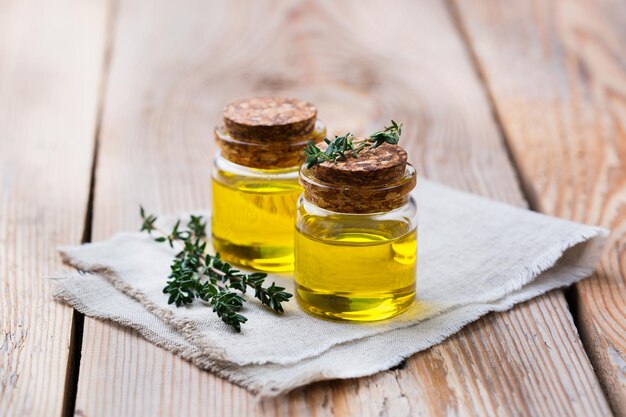 Saúde e beleza ainda conceito de vida Óleo essencial orgânico de tomilho em uma pequena jarra de vidro com folhas verdes em uma mesa de madeira rústica