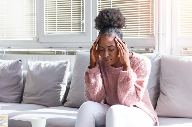 Saúde e dor estressada exausta jovem mulher negra com forte tensão dor de cabeça closeup retrato de bela menina doente sofrendo de enxaqueca cabeça sentindo pressão e estresse