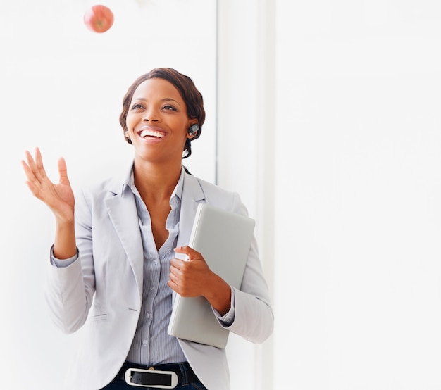 Saúde e negócios andam de mãos dadas para ela Uma jovem empresária afro-americana jogando uma maçã no ar