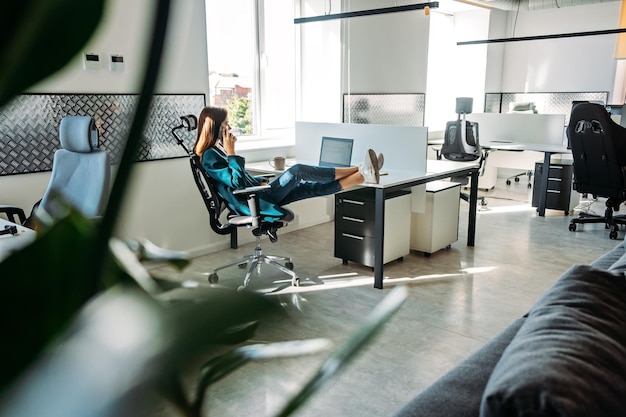 Foto saúde mental no local de trabalho empresária falando ao telefone e relaxando no