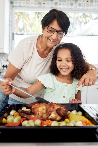 Saúde na cozinha e uma avó cozinhando com o neto em sua casa juntos para o dia de ação de graças As crianças adoram e um assado com uma mulher idosa preparando uma refeição com uma menina para nutrição alimentar