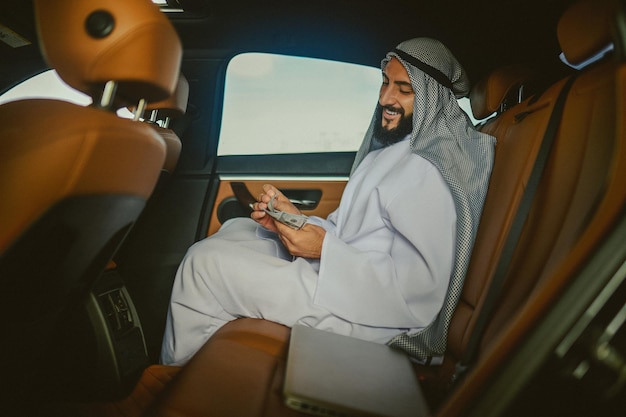 Saudi-Mann in traditioneller Kleidung in einem Auto mit Geld