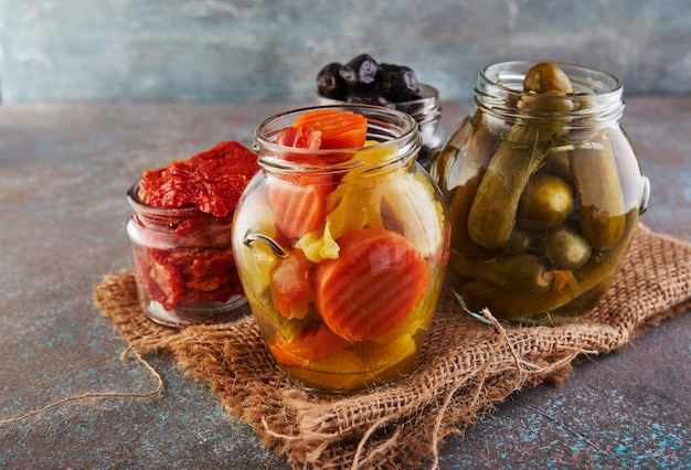 Foto sauerkraut, eingelegte karotten, eingelegte gurken, eingelegte oliven und oliven, getrocknete tomaten in gläsern