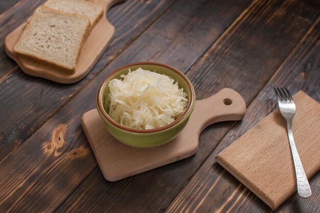 Sauerkraut in einem Teller und ein Stück Brot auf Holzhintergrund