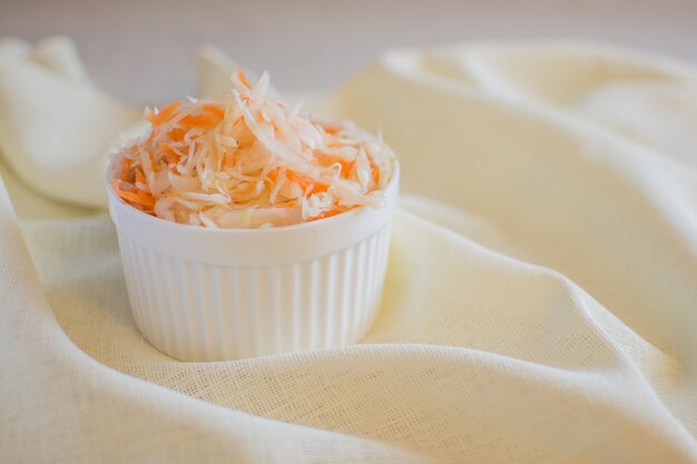Sauerkraut in einer weißen Keramikschale. Hausgemachtes Sauerkraut mit Karotten. Fermentiertes Essen.