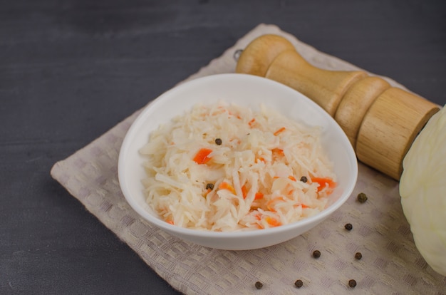 Sauerkraut und Karotten in einem Teller. horizontale Ansicht von oben, rustikaler Stil. Fermentiertes Essen. Speicherplatz kopieren.
