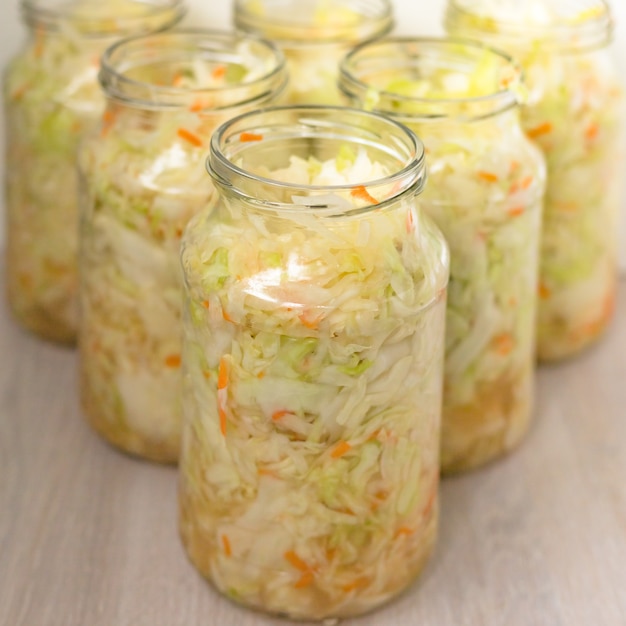 Sauerkrautfermentation in Glastopfdose. Von Milchsäurebakterien fermentierter Weißkohl schneiden. Nahansicht. Selektiver Fokus. Speicherplatz kopieren