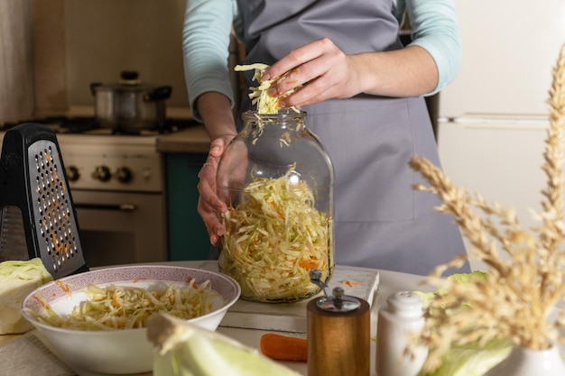 Sauerkrautkonserven Eine junge Frau bereitet in der Küche hausgemachtes Sauerkraut mit Karotten zu