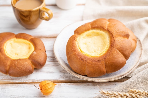 Sauerrahmbrötchen mit Tasse Kaffee auf weißem Holzhintergrund Selektiver Fokus der Seitenansicht