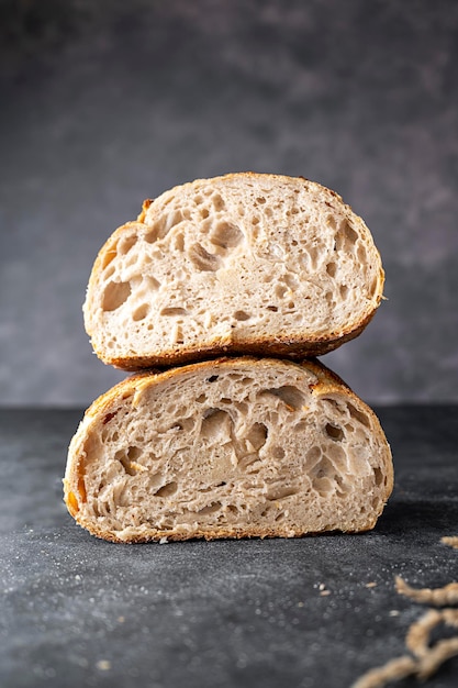 Sauerteig Handwerker hausgemachtes Brot in Hälften geschnitten auf dunklem Hintergrund.