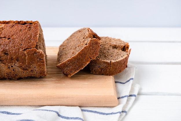 Sauerteig-Roggenbrot auf einem Schneidebrett auf weißem Holztisch mit Kopierraum geschnitten copy