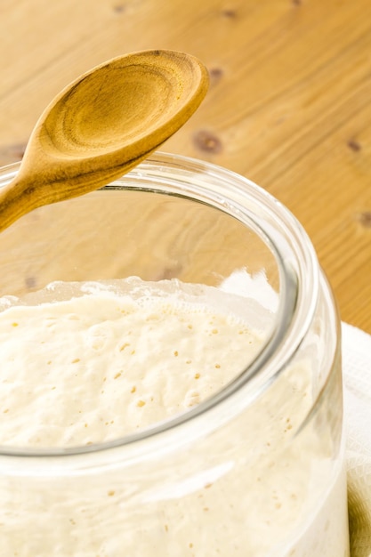 Sauerteigstarter im großen Glasgefäß auf dem Tisch.