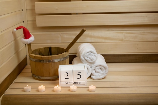 Sauna. Toallas, velas encendidas y un calendario para el 25 de diciembre, un cubo de madera con una cuchara.