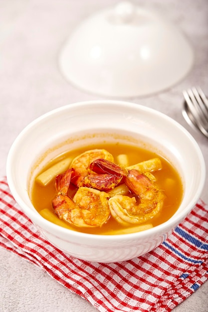 Saure Suppe mit Lotusstiel und Garnelen in einer weißen Schüssel auf dem Tisch lokale Speisen aus Thailand